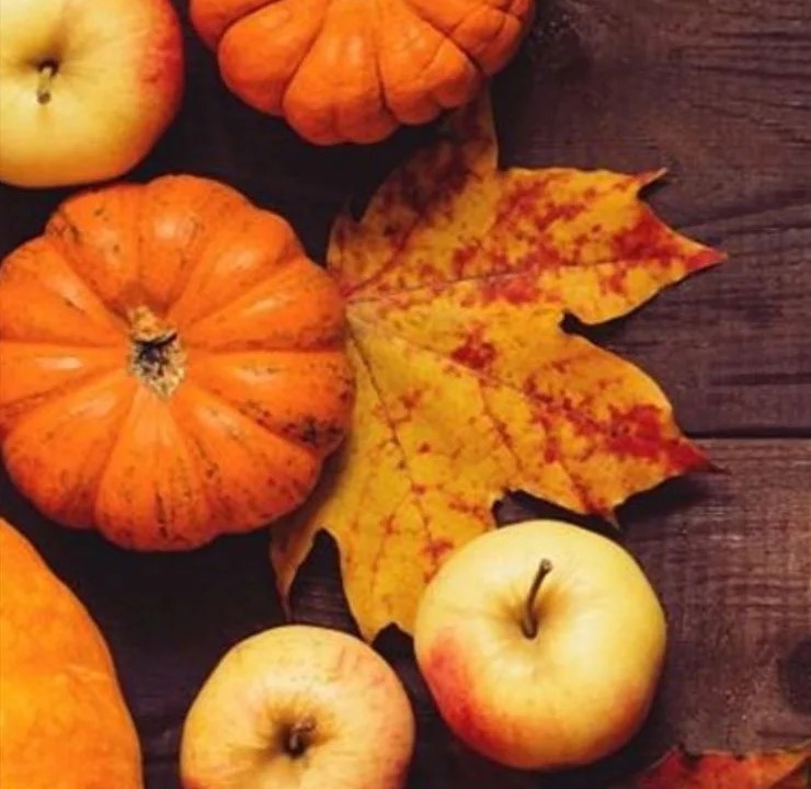 Pumpkins, apples and autumn leaves on a wooden table